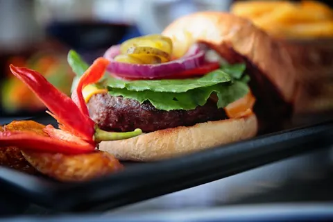 A beef burger with peppers and red onion