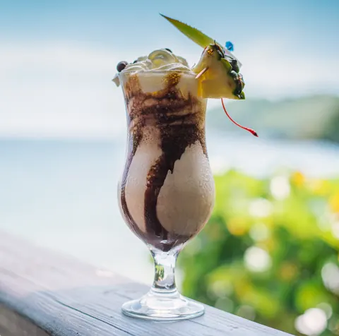 A frozen cocktail garnished with pineapple on the deck rail