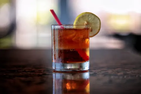 An iced drink with a slice of lemon on the bar