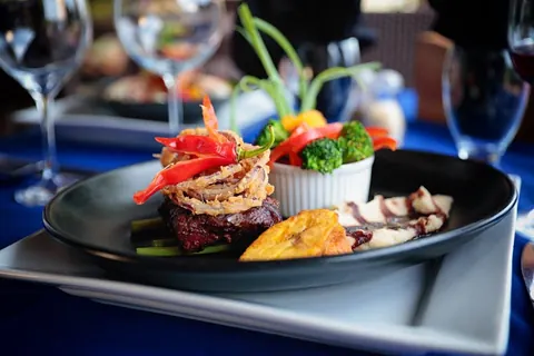 Steak topped with crispy onions, with grilled vegetables